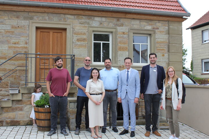 v.r.n.l.: Flächensparmanagerin Anne Weiß, Regionalmanager David Wald, Landrat Florian Töpper, Bürgermeister Johannes Grebner, Angelina Merthen (Hausbesitzerin), Simon Gößmann vom Amt für Ländliche Entwicklung; Veit Rudolph (Hausbesitzer) mit Tochter Greta ganz links. Foto: Paul Weichert.